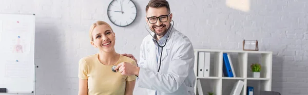 Médecin heureux et patient regardant la caméra pendant les diagnostics à la clinique, bannière — Photo de stock