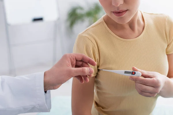 Partial view of woman taking electronic thermometer from physician in clinic — Stock Photo