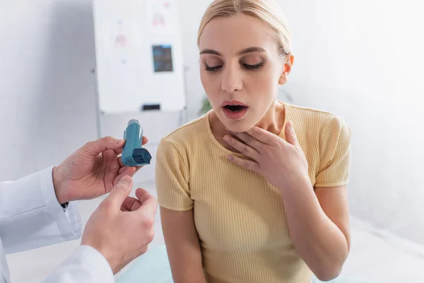 Médecin tenant inhalateur près de la femme toucher la gorge tout en souffrant d'asthme — Photo de stock