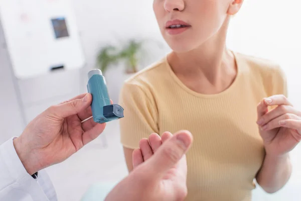 Visión parcial de la mujer asmática cerca del médico con inhalador - foto de stock