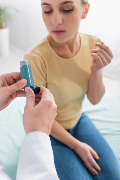 Médico sosteniendo inhalador cerca de la mujer asmática en el hospital - foto de stock