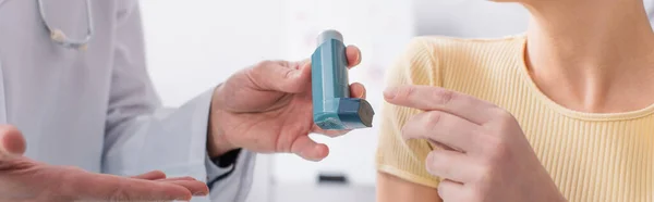 Inhaler in hand of doctor near asthmatic woman, cropped view, banner — Stock Photo