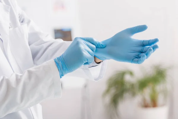 Cropped view of doctor putting on blue latex gloves in hospital — Stock Photo