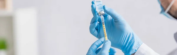 Partial view of doctor in blue latex gloves filling syringe with coronavirus vaccine, banner — Stock Photo