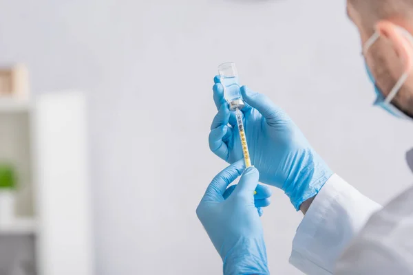 Cropped view of doctor in latex gloves filling syringe with vaccine — Stock Photo