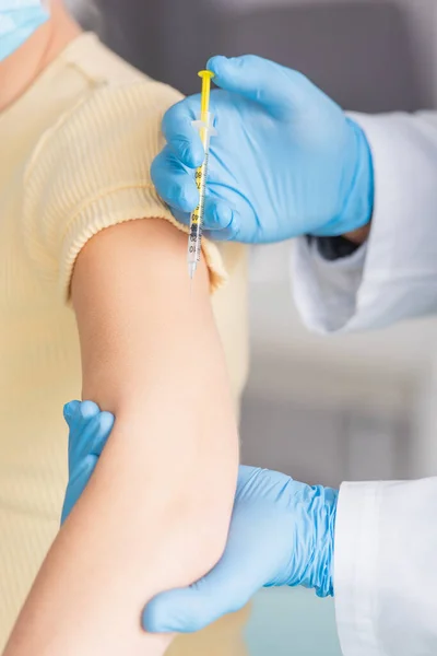 Vista recortada del médico en guantes de látex vacunar a la mujer - foto de stock