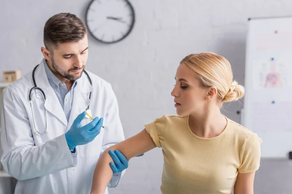 Médico en guantes de látex que administra la inyección de vacuna a la mujer - foto de stock