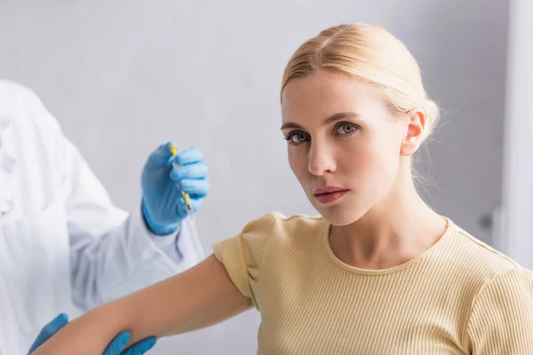 Femme blonde regardant la caméra pendant la vaccination à la clinique — Photo de stock