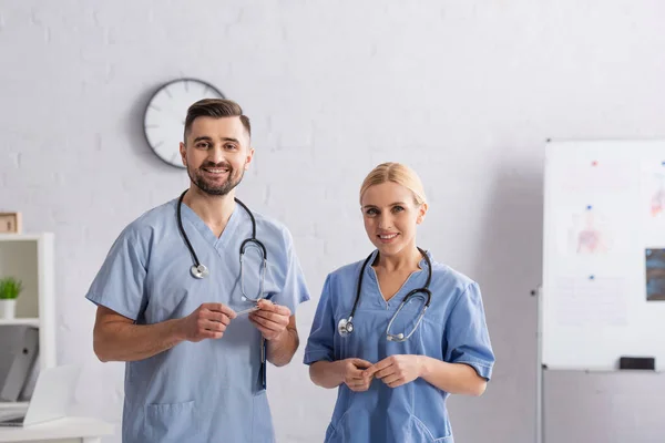 Médicos sonrientes en uniforme azul sonriendo a la cámara en el hospital - foto de stock