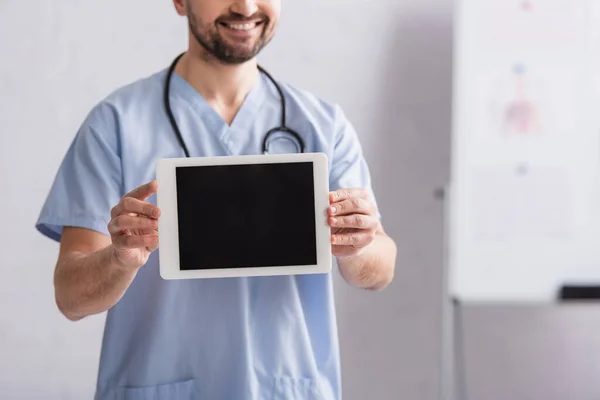 Partial view of smiling doctor showing digital tablet with blank screen — Stock Photo