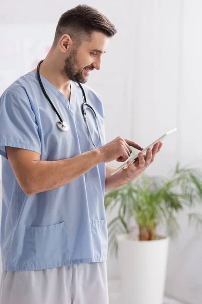 Médico sonriendo mientras señala con el dedo a la tableta digital - foto de stock