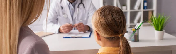 Rückansicht von Mutter und Tochter bei verschwommenem Kinderarzt in Klinik, Banner — Stockfoto