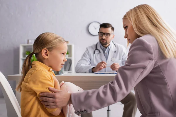 Besorgtes Kind schaut Mutter nahe verschwommenem Arzt im Krankenhaus an — Stockfoto