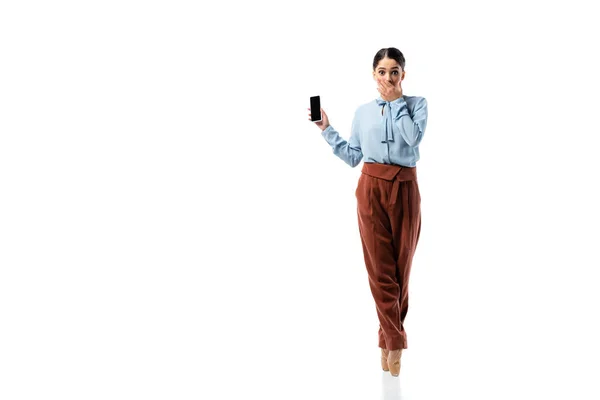 Bailarina asombrada sosteniendo smartphone y cubriendo la boca sobre fondo blanco - foto de stock