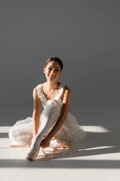 Young ballerina wearing pointe shoes on grey background — Stock Photo
