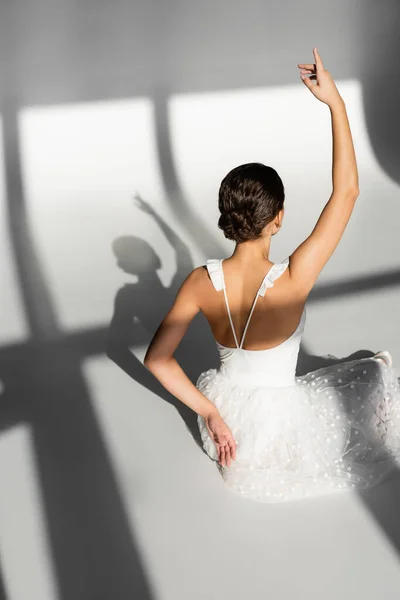 Back view of ballerina sitting on grey background — Stock Photo