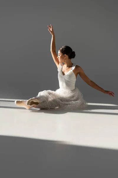 Vue latérale de l'élégante ballerine assise sur fond gris — Photo de stock