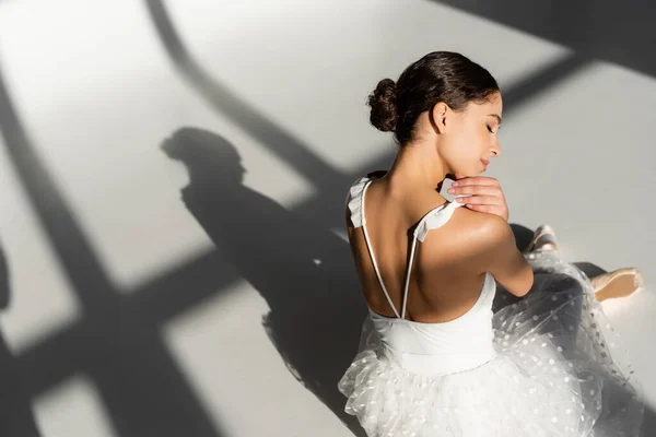 Vista de ángulo alto de la bailarina sentada sobre fondo gris - foto de stock