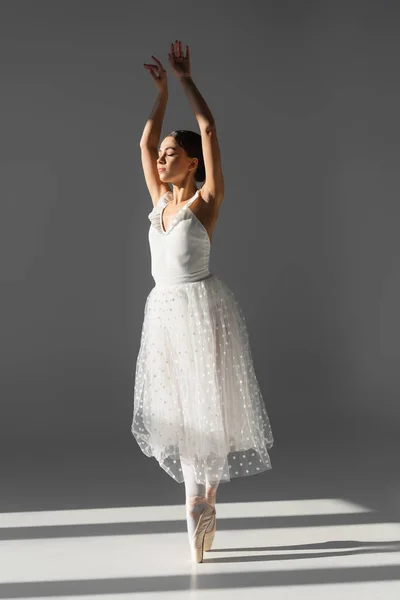 Ballerina dancing with closed eyes on grey background — Stock Photo