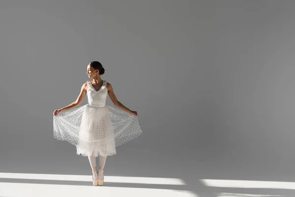 Side view of ballerina holding skirt on grey background — Stock Photo