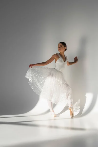 Bailarina profesional sosteniendo falda sobre fondo gris con sombra - foto de stock