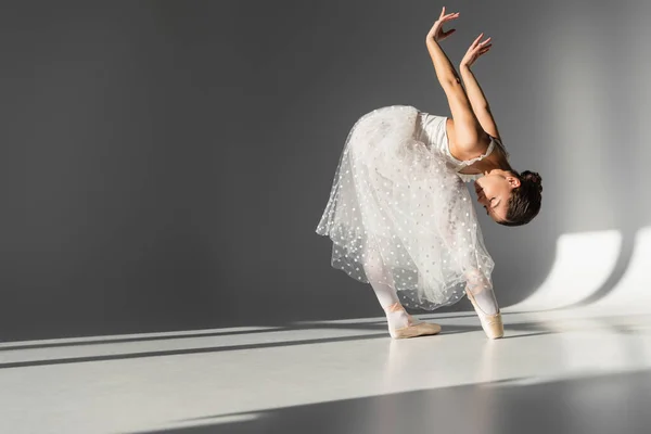 Вид збоку балерини, що згинається на сірому фоні — стокове фото