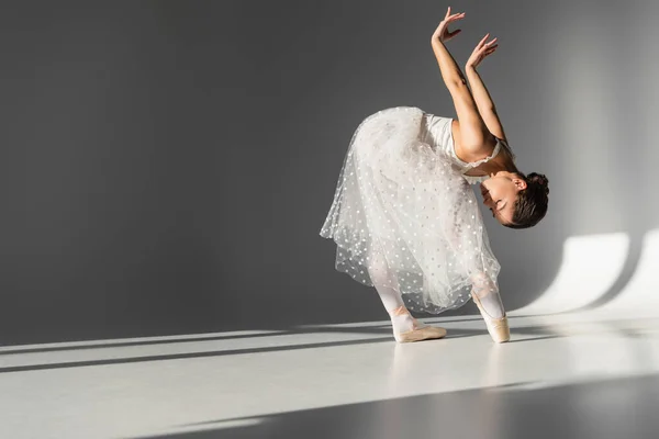 Vue latérale de la ballerine penchée sur fond gris — Photo de stock