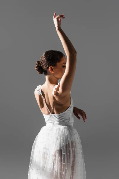 Elegant ballerina raising hand isolated on grey — Stock Photo