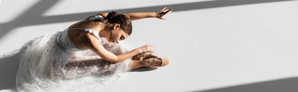 Hochwinkelaufnahme der Ballerina in Spitzenschuhen, die sich auf grauem Hintergrund mit Sonnenlicht beugt, Banner — Stockfoto