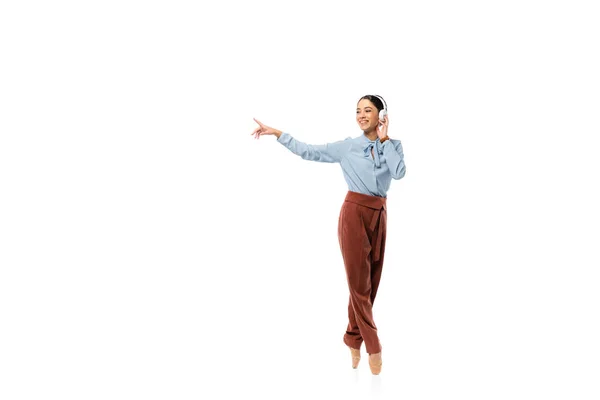 Bailarina sorridente em fones de ouvido apontando com o dedo isolado em branco — Fotografia de Stock