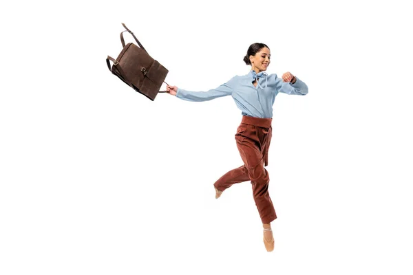 Bailarina alegre olhando para relógio de pulso enquanto segurando mochila isolada no branco — Fotografia de Stock