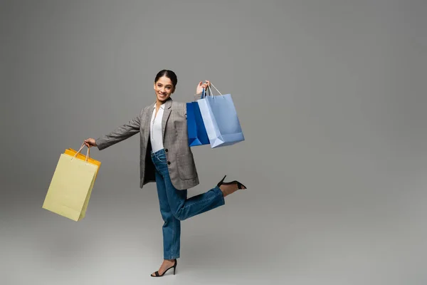 Красивая женщина держит сумки для покупок на сером фоне — стоковое фото