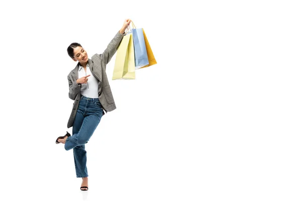 Mujer sonriente que señala con el dedo el bolso de la compra sobre fondo blanco - foto de stock