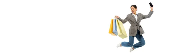 Donna stupita con borse della spesa e smartphone che salta isolato su bianco, banner — Foto stock