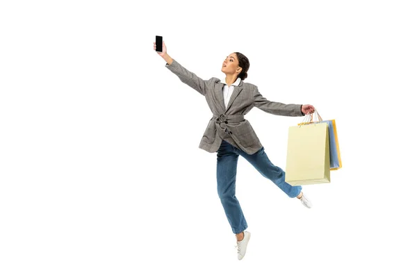 Балерина з сумками, що тримають мобільний телефон, під час стрибка ізольованою на білому. — стокове фото
