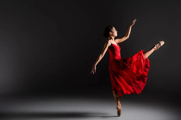 Vue latérale de la ballerine dansant une jambe sur fond noir — Photo de stock