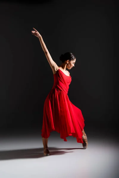 Side view of young ballerina dancing on black background — Stock Photo