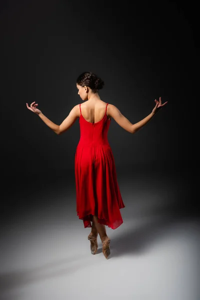 Vue latérale de la ballerine en robe rouge regardant loin sur fond noir — Photo de stock