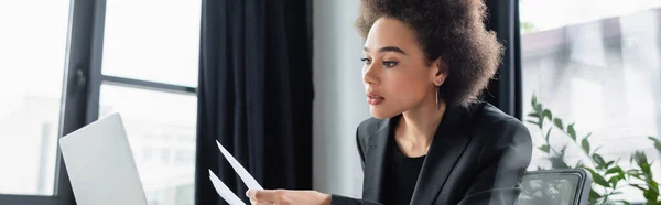 Mujer de negocios afroamericana elegante que trabaja con documentos en la oficina, bandera - foto de stock