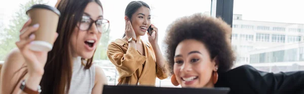 Erstaunt interracial Geschäftspartner in der Nähe asiatische Frau spricht auf Smartphone, Banner — Stockfoto