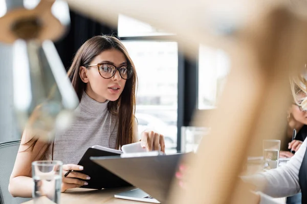 Brünette Geschäftsfrau mit Brille arbeitet mit Dokumenten im verschwommenen Vordergrund — Stockfoto