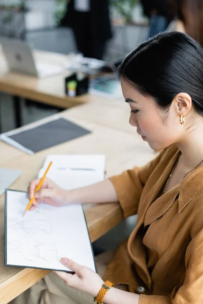 Asiatique styliste dessin croquis sur lieu de travail dans bureau — Photo de stock