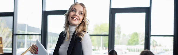 Щаслива блондинка бізнес-леді з цифровим планшетом посміхається в офісі, банер — стокове фото