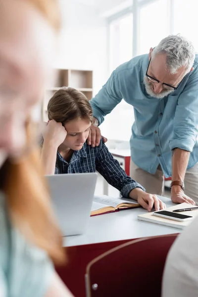 Insegnante in piedi vicino triste scolaro in classe — Foto stock