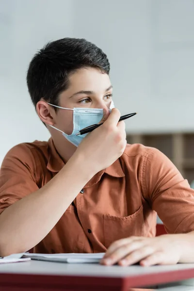 Schoolboy segurando caneta e usando máscara médica — Fotografia de Stock
