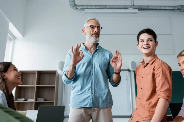 Enseignant positif montrant des signes acceptables près des élèves adolescents — Photo de stock