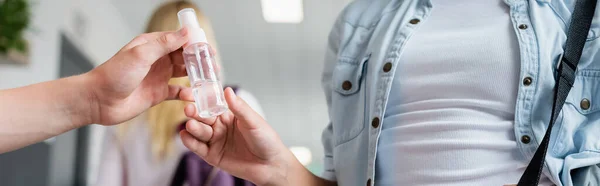 Partial view of guy giving hand sanitizer to girl at school, banner — Stock Photo