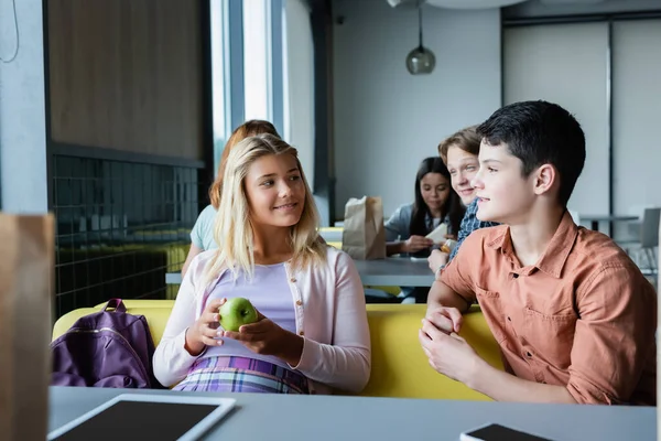 Друзья-подростки разговаривают во время обеденного перерыва в школьной столовой — стоковое фото