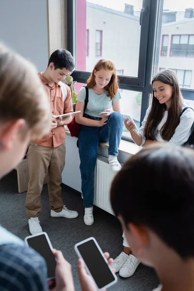 Teenager benutzen Geräte im Schulflur auf verschwommenem Vordergrund — Stockfoto