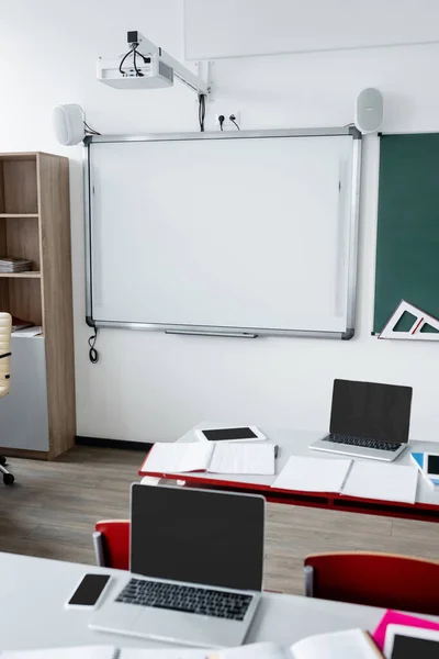 Modernes Klassenzimmer mit Radierbrett an der Wand und digitalen Geräten auf dem Schreibtisch — Stockfoto